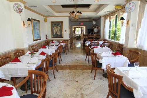 a restaurant with white tables and chairs and a chandelier at Hotel Chateaubleau in Miami