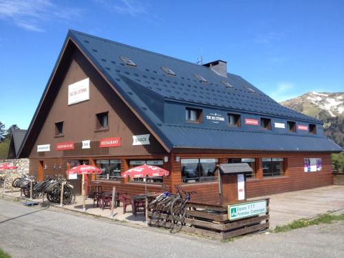 a large wooden building with tables and umbrellas at Hôtel Le Tuc de l'Etang in Boutx