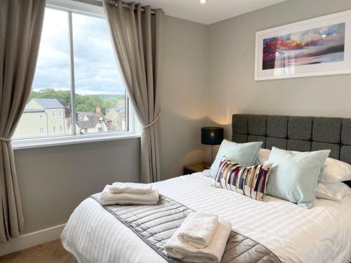 a bedroom with a large bed with towels on it at Urban Living's - The Wren Beautiful City Centre Apartment with Parking in Oxford