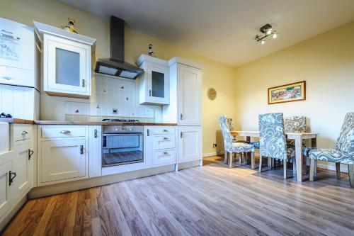 cocina con armarios blancos, mesa y sillas en De Courceys Manor Suites & Cottages, en Cardiff