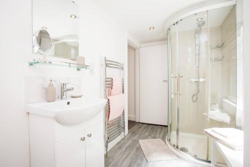 a white bathroom with a sink and a shower at Victoria Apartment 1 in Torquay