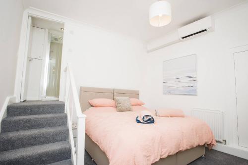 una camera con letto rosa e scala di Victoria Apartment 1 a Torquay