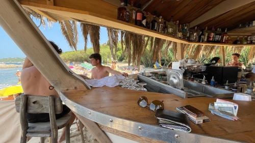 un homme assis au bar de la plage dans l'établissement VOILES ST TROPEZ APARTEMENTS, à Saint-Tropez