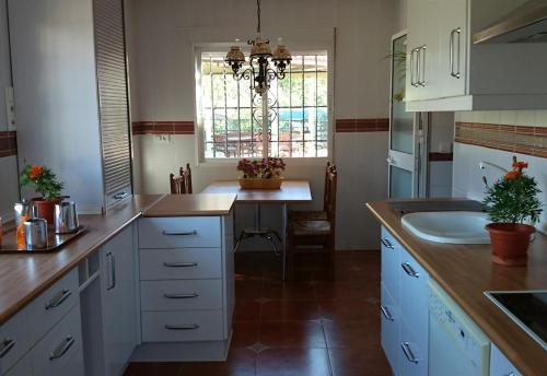 een keuken met witte kasten, een gootsteen en een raam bij Finca Santa Matilde Málaga in Málaga