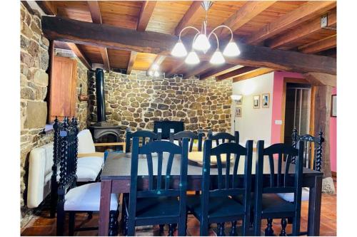 AIRE DE MONTAÑA - ESTUPENDAS VISTAS A LOS PICOS في Baró: غرفة طعام مع طاولة وكراسي وجدار حجري