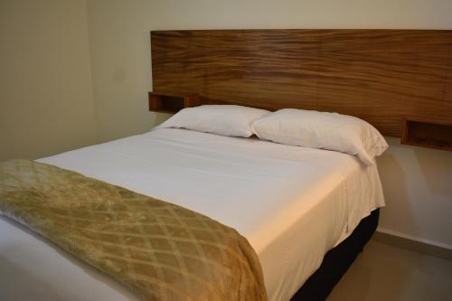 1 dormitorio con 1 cama blanca grande y cabecero de madera en Casa Bonanza para 8 personas en Playa del Carmen, en Playa del Carmen