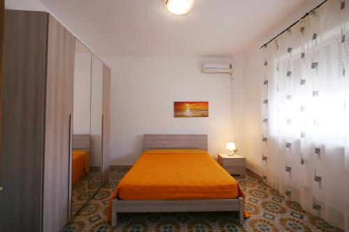um quarto com uma cama com uma colcha laranja em appartamento a 20 metri dalla spiaggia em Torre Lapillo