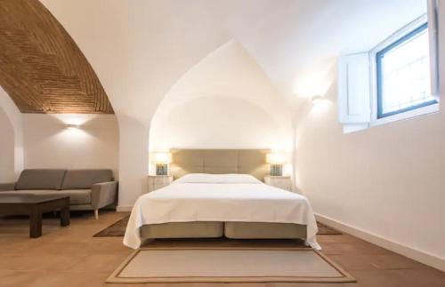 a white bedroom with a bed and a couch at Casa do Sembrano in Beja