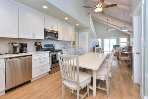 a kitchen with white cabinets and a table and chairs at Lily Pad in Oak Island