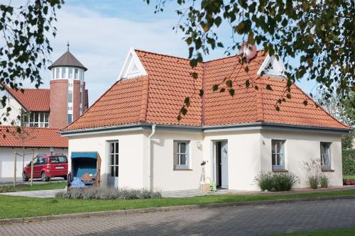 een klein wit huis met een oranje dak bij Ferienhaus Yvonne in Otterndorf