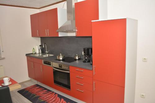 cocina con armarios rojos y fogones en Ferienwohnung Elisabeth, en Egloffstein