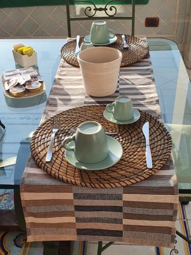 a table with plates and utensils on a glass table at La Finestra sul Mare in Ischia