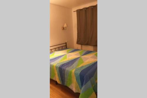 Un dormitorio con una cama con una colcha colorida. en superbe appartement T3 traversant avec place de parking, en Rodez