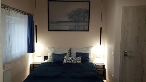 1 dormitorio con 1 cama azul y 2 lámparas en Sarokház Tihany en Tihany