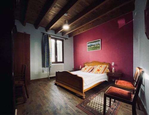 Chez Routcho في Saint-Sauveur-de-Peyre: غرفة نوم بسرير وجدار احمر