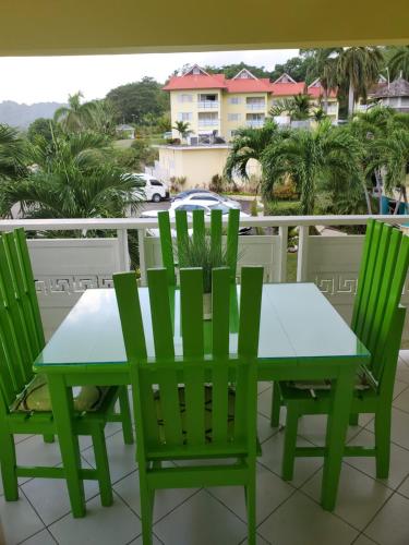 uma mesa verde e cadeiras numa varanda em Mystic Ridge Paradise em Ocho Rios