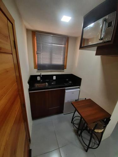 a small kitchen with a sink and a table at Flats Ouro Gramado Localizado a 900 metros da entrada do Centro de Gramado in Gramado