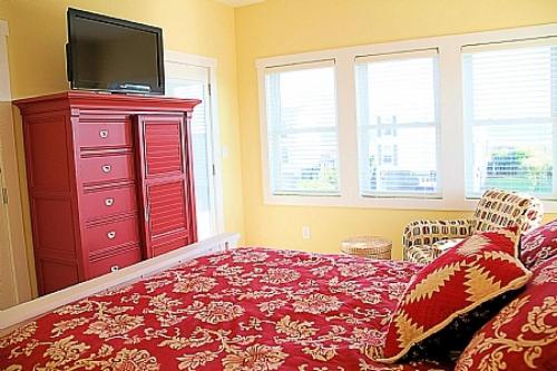a bedroom with a red dresser with a tv on top at 1 More Day in Oak Island