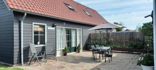 een huis met een tafel en stoelen en een paraplu bij Beachloft Zeeland 1 in Scharendijke