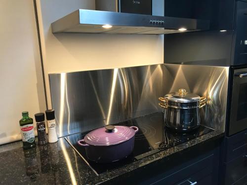 a stove top with a pot and a pan on it at La Maison Bleue, luxury self-catering villa. in Langebaan