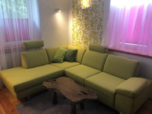a living room with a green couch and a table at Romantikapartment mit Sommercard in Ramsau am Dachstein