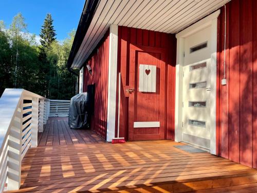 a red door on a house with a wooden deck at Cozy renovated house with a lot of parking space. in Haparanda