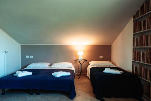 two beds in a room with a book shelf at Il Pozzo Country House in Collescipoli