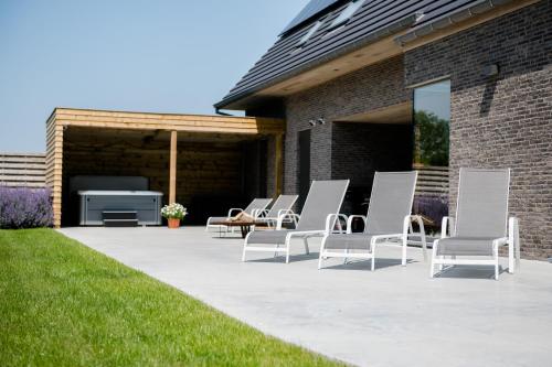 a group of white chairs sitting on a patio at Coq au lit: Maison d'étoile in De Haan