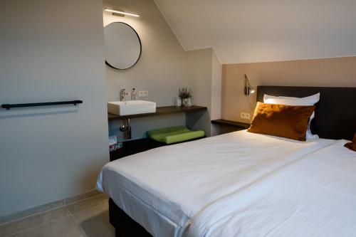 1 dormitorio con 1 cama blanca grande y lavamanos en Coq au lit: Maison d'étoile, en De Haan