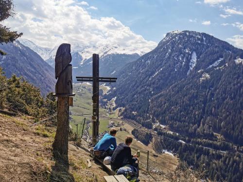 two people sitting on a bench next to a cross at Ferienwohnung Eller 79 in Vals