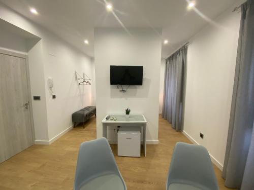 a room with chairs and a tv on a wall at Apartamentos de Don Juan in Úbeda