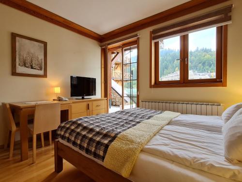 a bedroom with a bed and a desk and a television at Apartman 120 Vucko in Jahorina