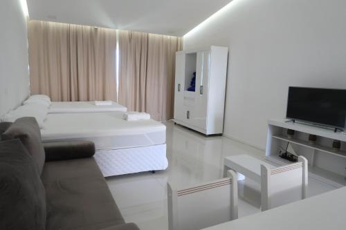 a white living room with a bed and a tv at Terra Nostra Residence in Porto De Galinhas