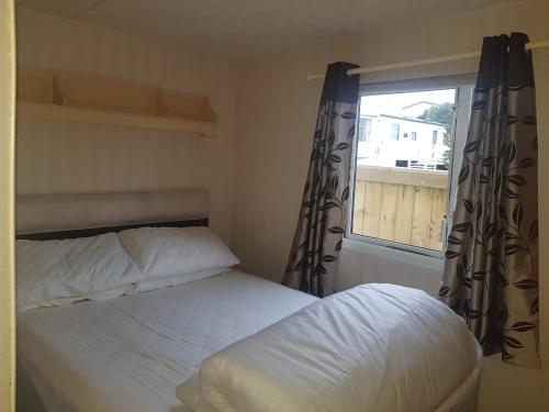 a small bedroom with a bed and a window at 6 Berth with private Garden - 69 Brightholme Holiday Park Brean! in Brean