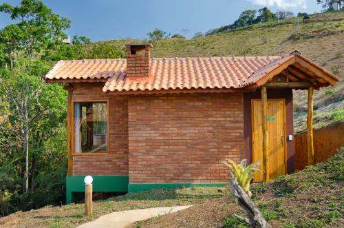 a small brick house with a red roof at Pousada Lua de Minas in Visconde De Maua