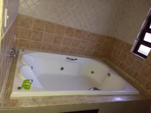 a white bath tub in a tiled bathroom at Pousada Finlândia in Penedo