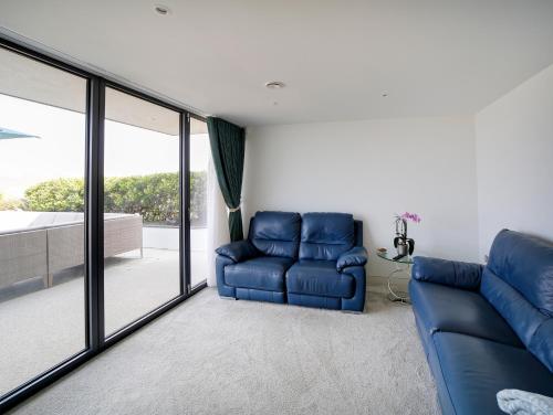 a living room with a blue couch and sliding glass doors at Megizzy in Polzeath