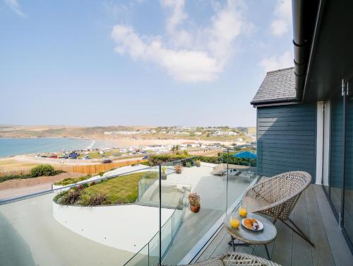 a balcony with a table and chairs and a view of the ocean at Megizzy in Polzeath