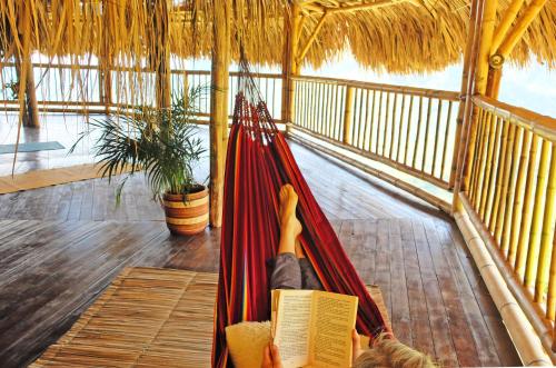 a person laying in a hammock reading a book at Ecohotel Soplo del Tambo in Cocorná
