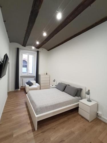 a white bedroom with a bed and a chair at Arco Antico in Alba