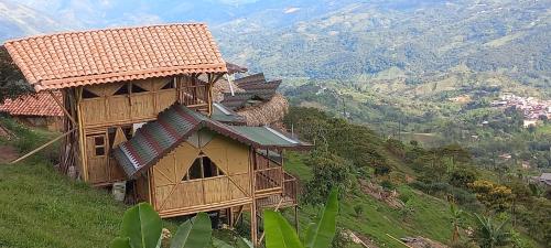 a group of houses on a hill with mountains in the background at Ecohotel Soplo del Tambo in Cocorná