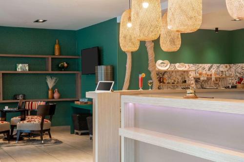 a salon with green walls and a table and chairs at Best Western Plus Hôtel Belfort Centre Gare in Belfort