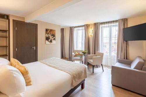 a hotel room with a bed and a couch and a table at Best Western Plus Hôtel Belfort Centre Gare in Belfort