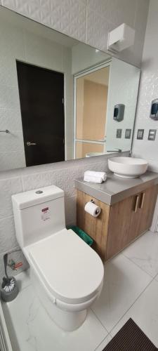 une salle de bain avec toilettes, lavabo et miroir dans l'établissement Penthouse con Roof Garden, experiencia sin igual., à Manzanillo