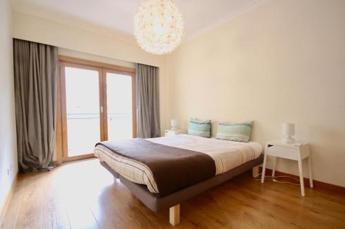 um quarto com uma cama grande e um lustre em Cozy Orange Telheiras Apartment em Lisboa