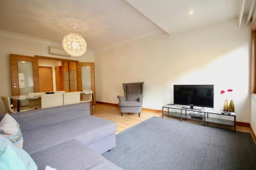 a living room with a couch and a flat screen tv at Cozy Orange Telheiras Apartment in Lisbon