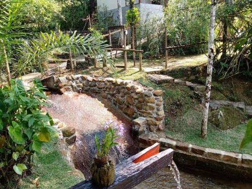 a garden with a stone wall and a bench at Pousada Vertente das Águas in Lumiar