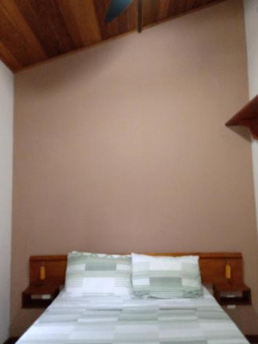 a bedroom with a bed with white sheets and pillows at Pousada Vertente das Águas in Lumiar