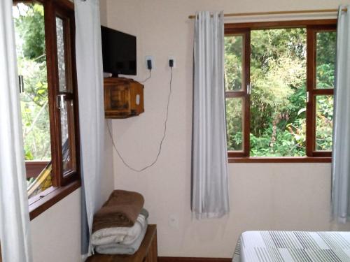 a room with a tv and a bed and windows at Pousada Vertente das Águas in Lumiar