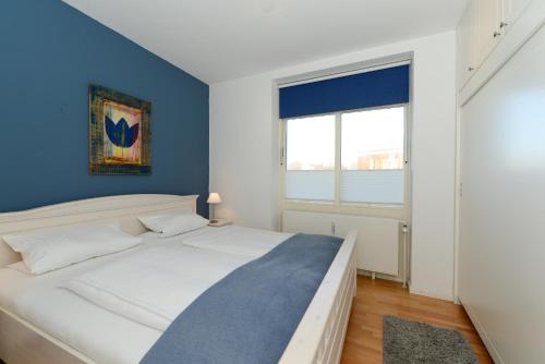 SüdstrandにあるHaus Bi de Wyk D8Bのベッドルーム1室(白いベッド1台、青い壁付)